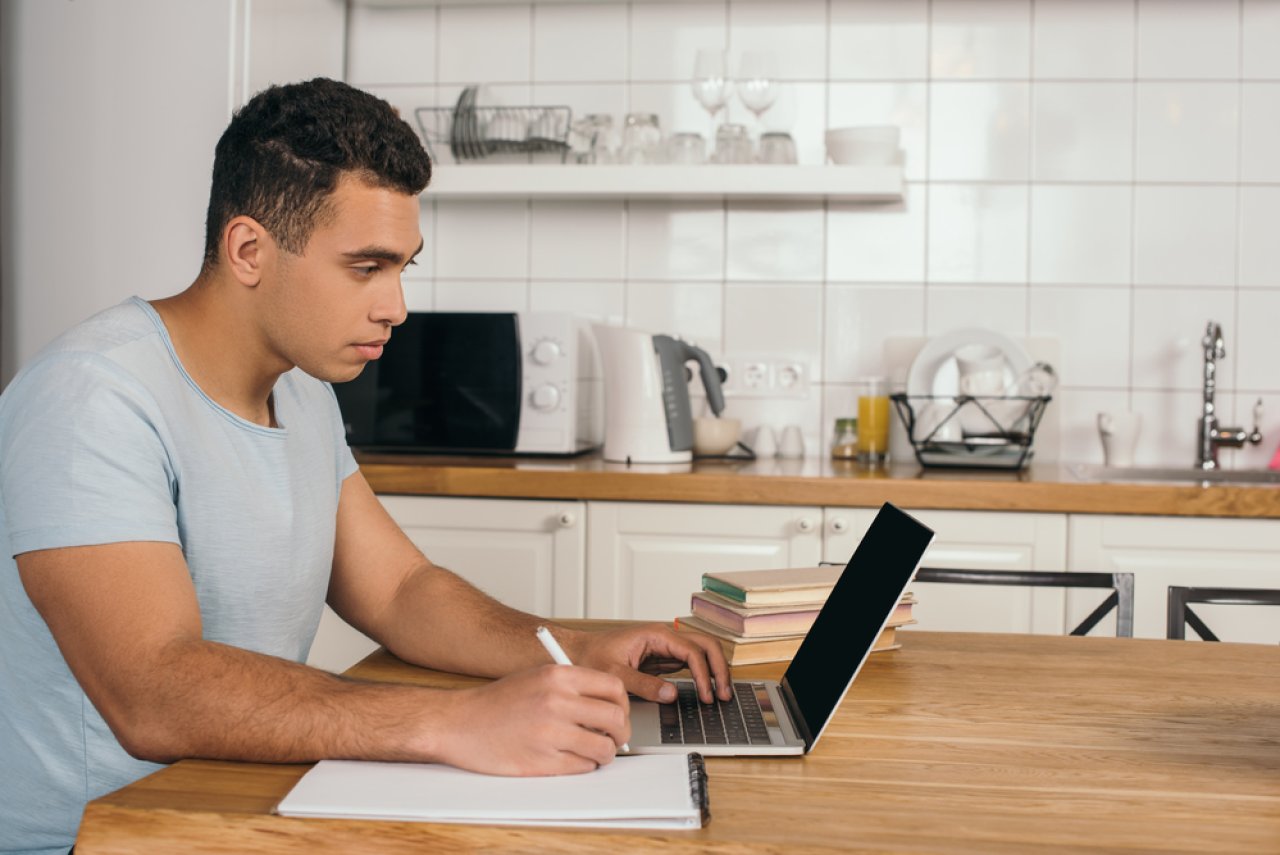 Man on laptop in his kitchen.