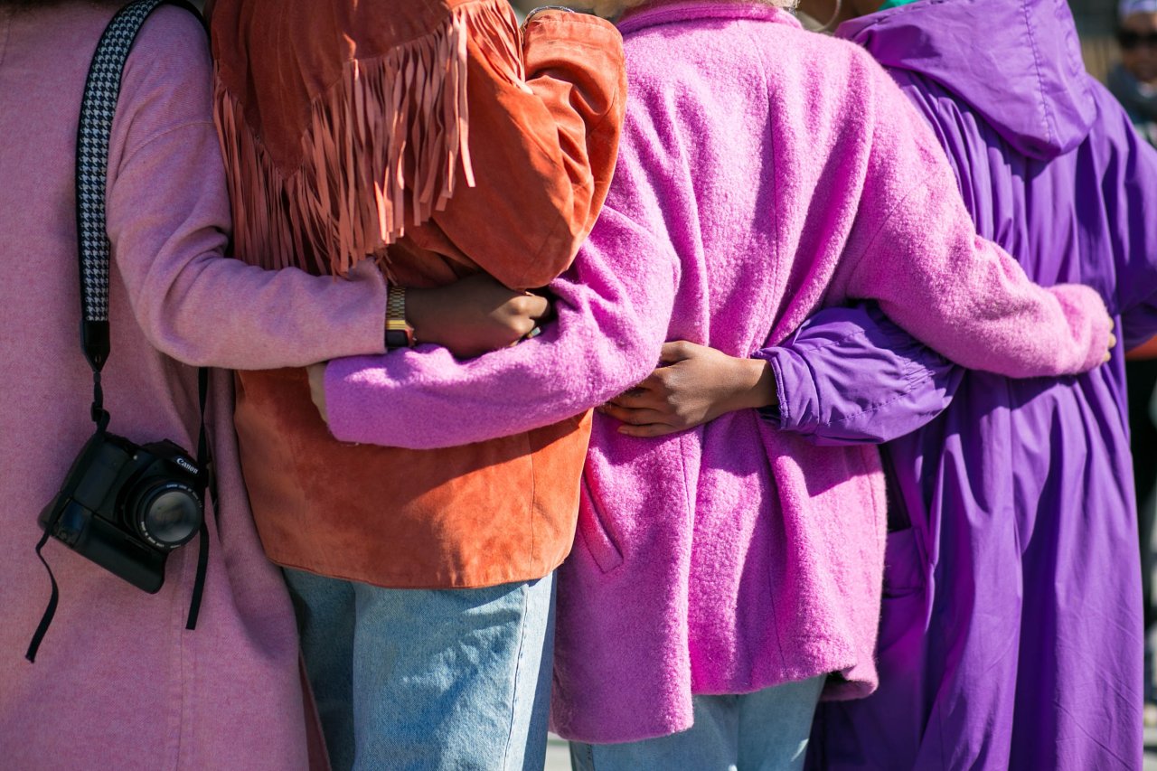 Woman in pink, arms around each other.
